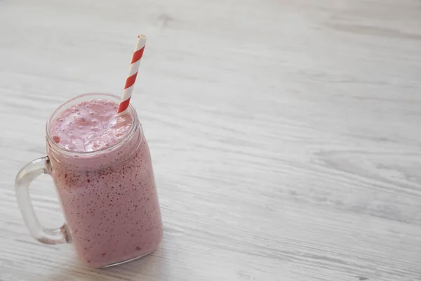 Smoothie à la banane aux fraises dans une tasse en verre sur bois blanc — Photo