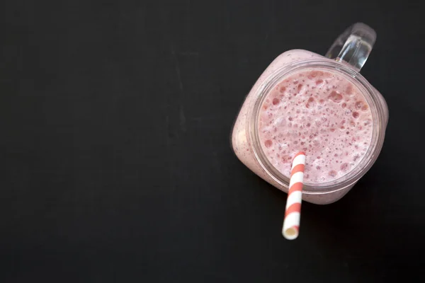 Smoothie à la banane aux fraises dans une tasse en verre sur fond noir — Photo