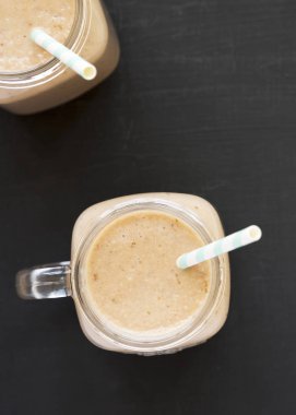 Siyah arka plan üzerinde cam kavanozlarda muz elma Smoothie, overh