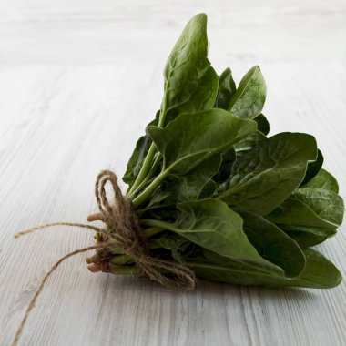 Beyaz ahşap yüzey, yan görünüm üzerinde taze çiğ ıspanak. Close