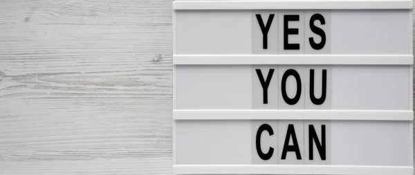 Palabras 'Sí puedes' en una caja de luz sobre fondo de madera blanco , — Foto de Stock