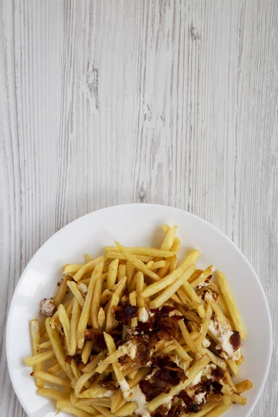 Tasty fast food: french fries with cheese sauce and bacon on a w — Stock Photo, Image