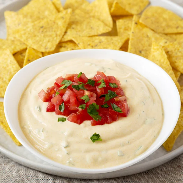 Homemade cheesy dip in a bowl, yellow tortilla chips, side view. — Stock Photo, Image