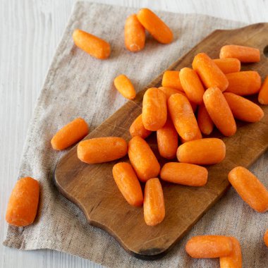 Rustik ahşap tahta üzerinde lezzetli soyulmuş bebek havuç, yan görünüm. C