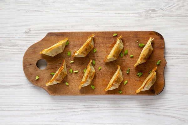 Domácí Gyoza na rustikální dřevěné desce nad bílou dřevěnou plochy — Stock fotografie