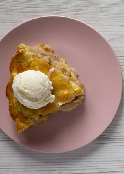 Rebanada de pastel de manzana con helado en un plato de color rosa en un woo blanco — Foto de Stock