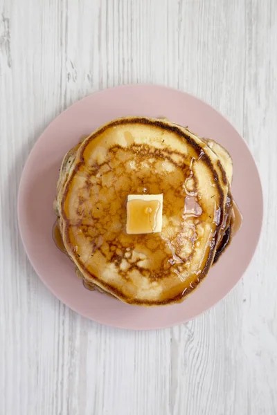 Hausgemachte Pfannkuchen mit Butter und Ahornsirup auf einem rosa Teller — Stockfoto