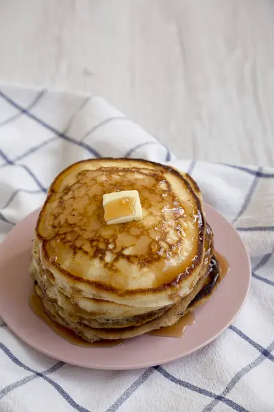 Hausgemachte Pfannkuchen mit Butter und Ahornsirup auf einem rosa Teller, — Stockfoto