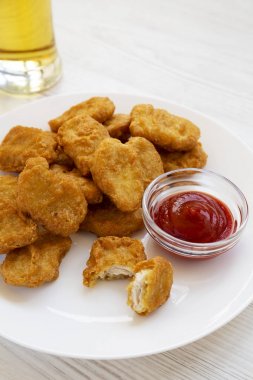 Beyaz w üzerinde ketçap ve soğuk bira bardak tavuk nuggets