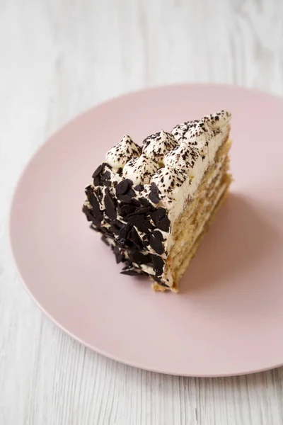 Ein Stück Tiramisu-Kuchen auf einem rosa Teller auf einer weißen hölzernen Surfa — Stockfoto