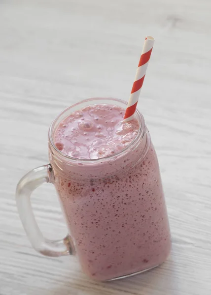 Smoothie à la banane aux fraises dans une tasse en verre sur bois blanc — Photo