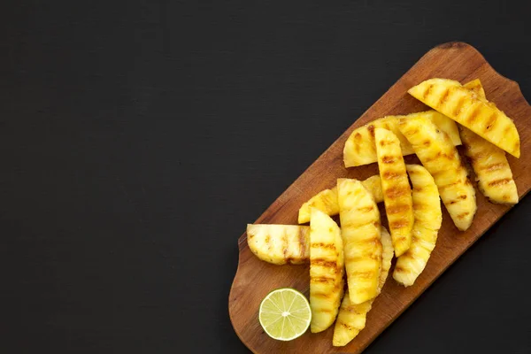 Zeppe di ananas alla griglia su una tavola di legno rustico su un nero sur — Foto Stock