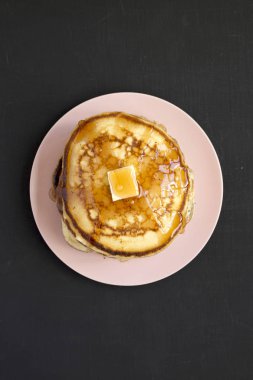 Pembe bir tabak üzerinde tereyağı ve akçaağaç şurubu ile ev yapımı krep, t