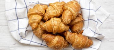 Beyaz ahşap arka plan üzerinde kumaş üzerinde taze pişmiş kruvasan, 