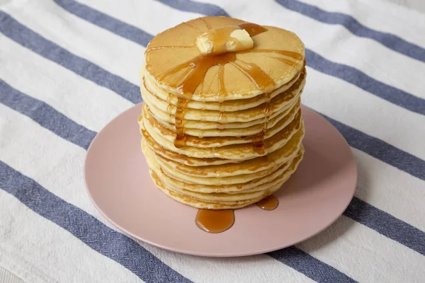 Stapel zelfgemaakte pannenkoeken met boter en ahornsiroop op een roze — Stockfoto