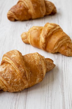 Beyaz ahşap yüzeyde taze kruvasan, düşük açılı görünüm. Clos