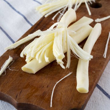 Rustik ahşap tahta üzerinde string peynir, yan görünüm. Sağlıklı atıştırmalık