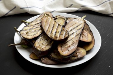 Siyah bir arka plan üzerinde beyaz bir tabak üzerinde Közlenmiş patlıcan, yan vi