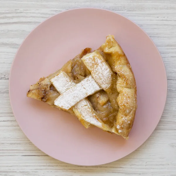 Rebanada de tarta de manzana casera en un plato de color rosa sobre una madera blanca — Foto de Stock