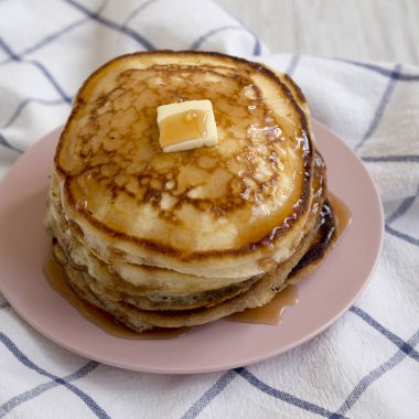 Pembe bir tabak üzerinde tereyağı ve akçaağaç şurubu ile ev yapımı krep, s