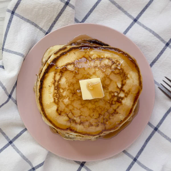 Hausgemachte Pfannkuchen mit Butter und Ahornsirup auf einem rosa Teller, o — Stockfoto