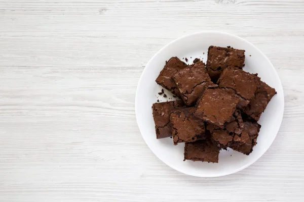 Homemade chocolate brownies on a white plate on a white wooden t — Stock Photo, Image