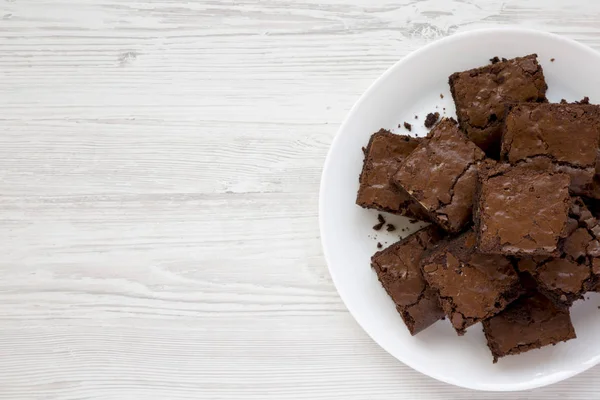 Homemade chocolate brownies on a white plate on a white wooden b — Stock Photo, Image