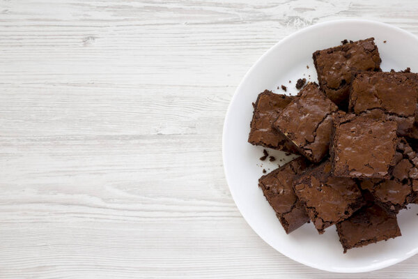 Домашние шоколадные брауни на белой тарелке на белом деревянном b
