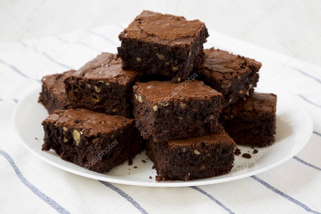 Homemade chocolate brownies on a white plate, side view. Close-u