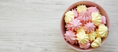 Beyaz ahşap yüzey üzerinde pembe bir kapta Mini bezeler, üst vie