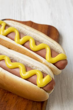 Beyaz bir w üzerinde rustik ahşap tahta üzerinde sarı hardal ile Hotdog