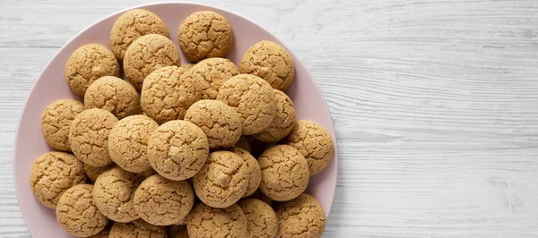 Galletas de almendras sobre un plato rosa sobre fondo de madera blanca, parte superior — Foto de Stock