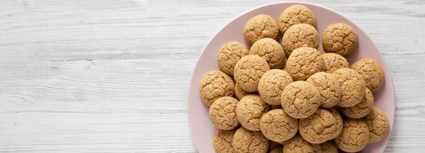 Galletas de almendras sobre un plato rosa sobre fondo de madera blanca, parte superior — Foto de Stock