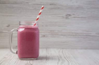 Beyaz ahşap arka planda bir cam kavanozda ahududu Smoothie, 