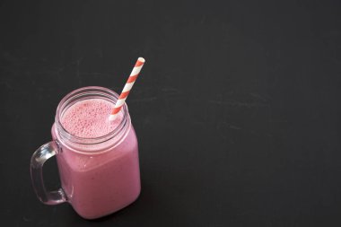 Siyah bir yüzeyde cam bir kavanozda ahududu Smoothie, düşük açı 