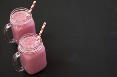 Siyah bir arka planda cam kavanozlarda ahududu Smoothie, yan Vie