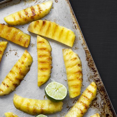 Siyah arka planda tepsi üzerinde kireç ile ızgara ananas, üst v