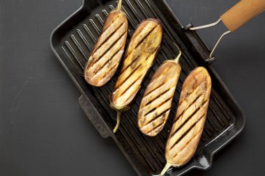 Siyah bir arka planda bir ızgara tava üzerinde patlıcan, üst görünüm. Düz