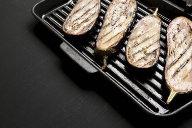 Siyah bir arka planda bir ızgara tava üzerinde patlıcan, yan görünümü. Polis