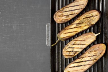 Siyah bir arka planda bir ızgara tava üzerinde patlıcan, üst görünüm. Düz