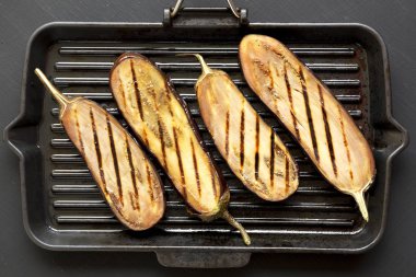 Siyah bir yüzeyde bir ızgara tava üzerinde patlıcan, havai görünümü. Fl