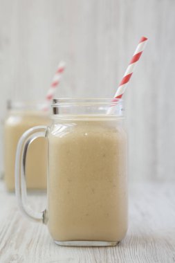 Beyaz ahşap ba cam kavanozlarda fıstık ezmesi muz Smoothie