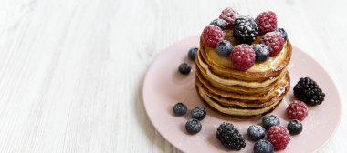 Beyaz ahşap backgrou üzerinde pembe bir plaka üzerinde çilek ile pancake