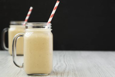 Cam kavanoz kupalar, yan görünümde fıstık ezmesi muz Smoothie. Kopya