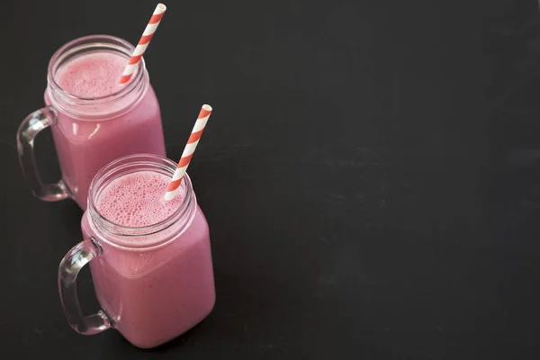 Raspberry smoothie in glass jars on a black background, side vie — Stock Photo, Image