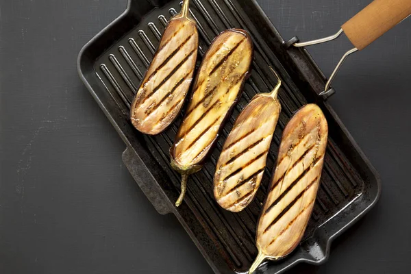 Siyah bir arka planda bir ızgara tava üzerinde patlıcan, üst görünüm. Düz