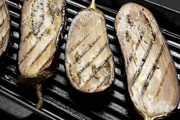 Berenjena en una sartén a la parrilla sobre un fondo negro, vista lateral. Clo. —  Fotos de Stock