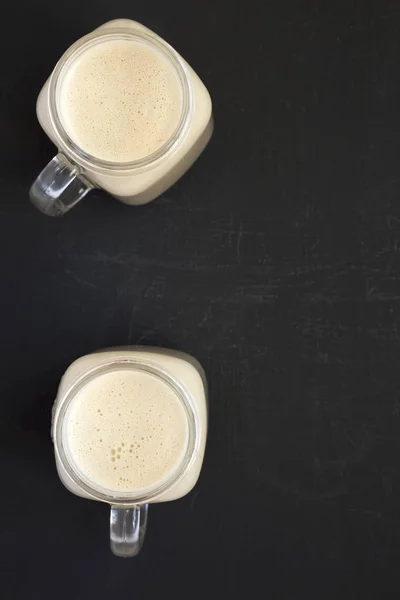 Peanut butter banana smoothie in glass jar mugs on a black backg — Stok Foto