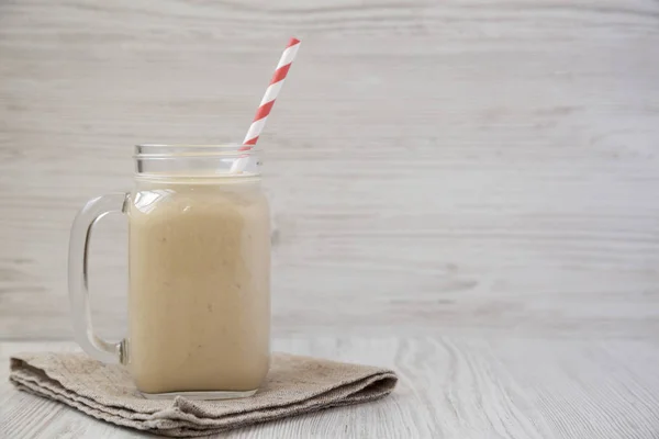 Beyaz ahşap b üzerinde bir cam kavanoz fıstık ezmesi muz Smoothie