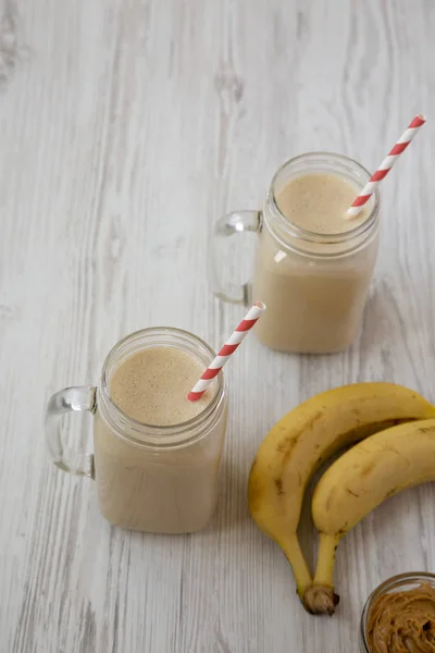 Jordnötssmör banan smoothie i glasburkar på en vit trä ta — Stockfoto